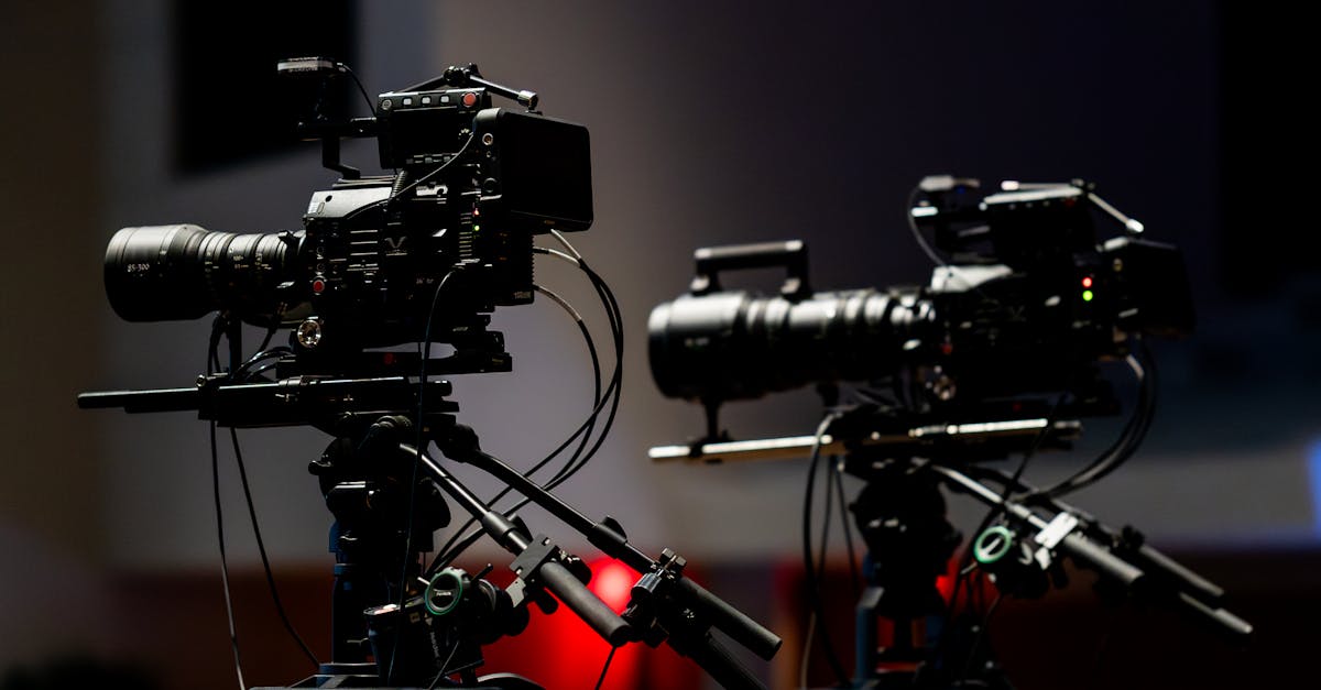 Two professional video cameras set up in a dimly lit studio environment ready for filming.