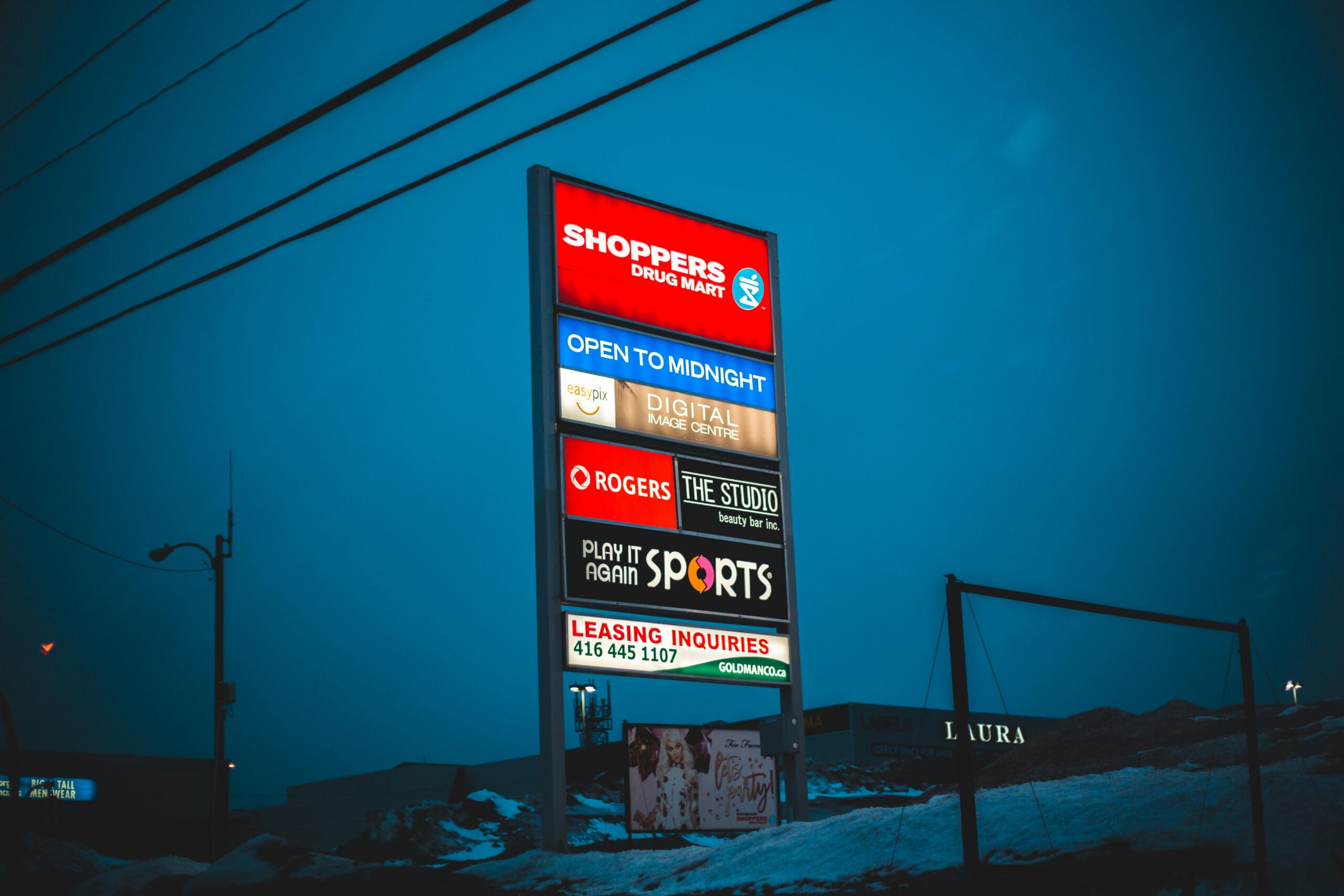 Illuminated big board with signs of shops and stores under dark sky in winter season